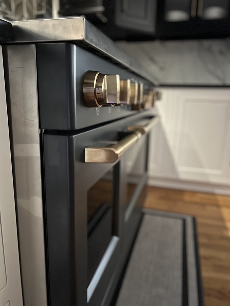 Close-up of matte black oven with brass hardware in Indian Hills, KY custom kitchen by Trade Works Remodeling