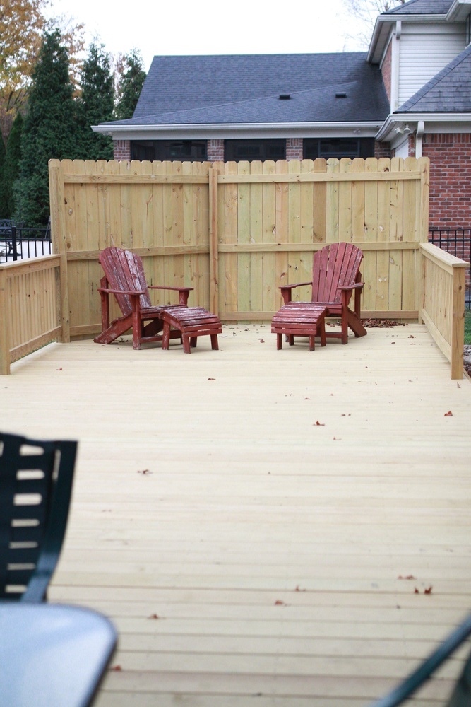 Outdoor space with privacy fence and red chairs in a custom home by Trade Works Remodeling in Plainview, KY