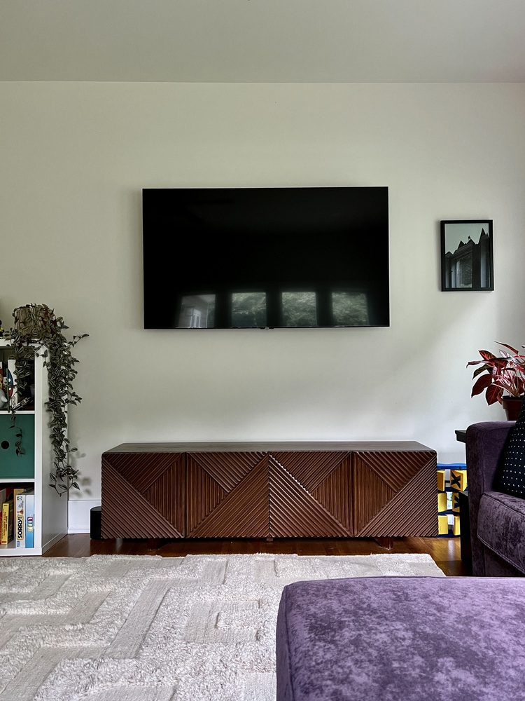 Entertainment wall with TV and wooden media console in Louisville home by Trade Works Remodeling