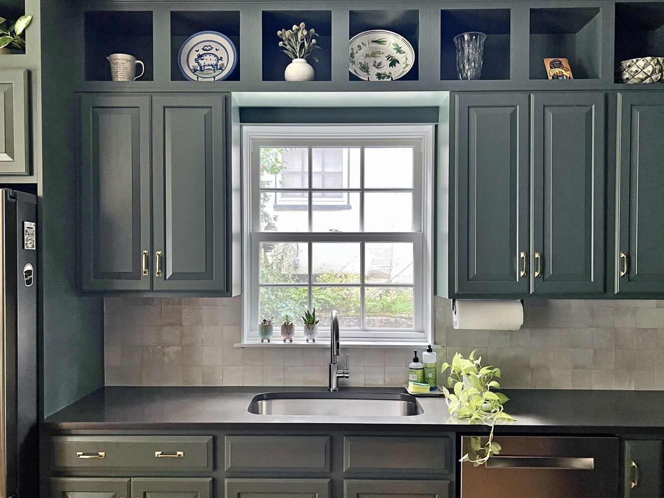 Refreshed kitchen sink view with dark cabinetry and plants in Louisville custom home by Trade Works Remodeling Refreshed kitchen sink view with dark cabinetry and plants in Louisville custom home by Trade Works Remodeling