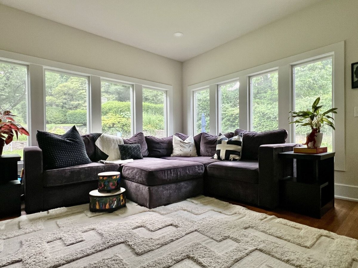 Sunlit living space with L-shaped sofa and panoramic windows in Louisville custom home by Trade Works Remodeling