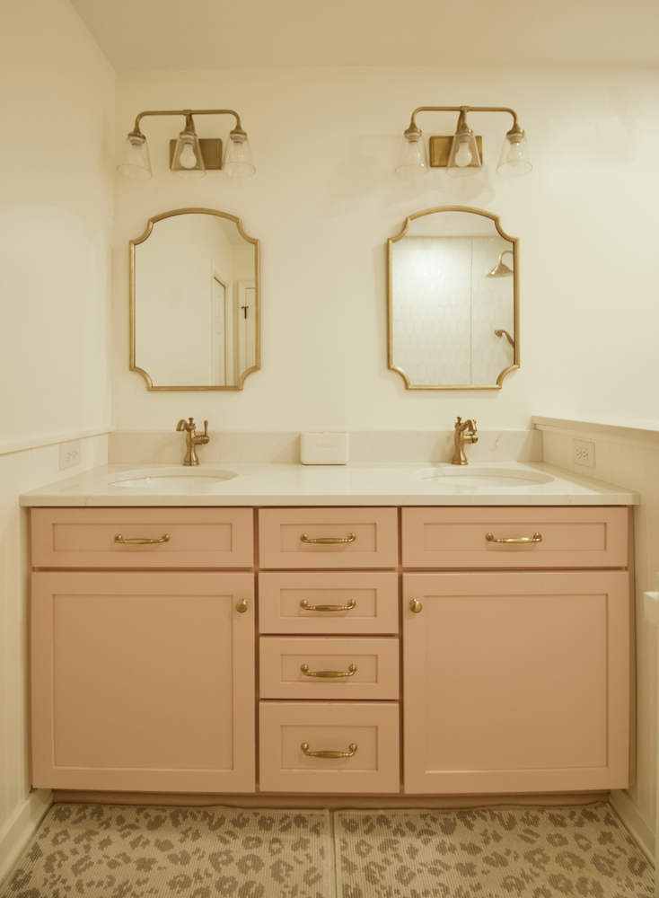 Bathroom remodel featuring pink double vanity with gold fixtures by Trade Works Remodeling in Louisville, KY