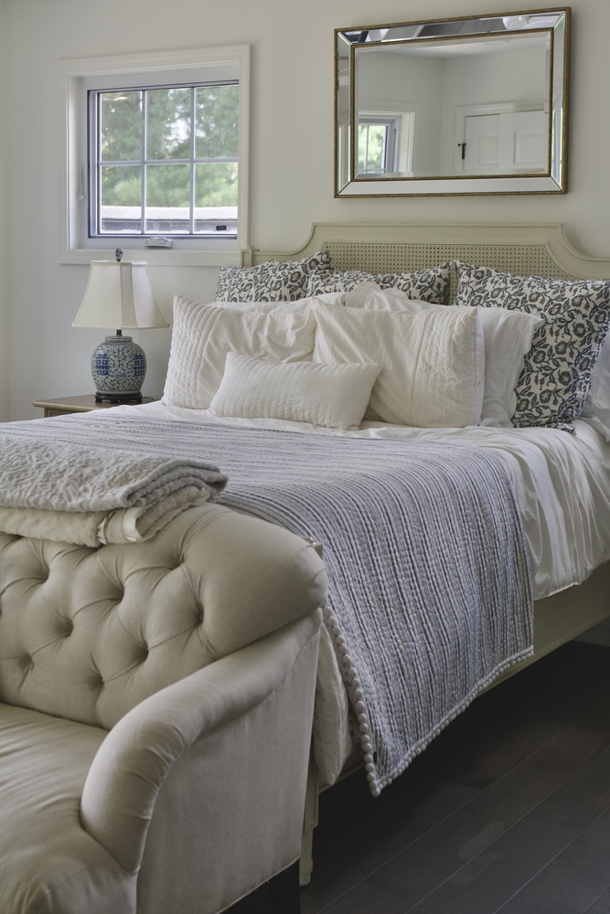 Cozy bedroom remodel with tufted bench and layered bedding by Trade Works Remodeling in St. Matthews, KY