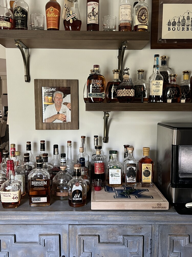 Custom bar area with whiskey collection and wood shelving by Trade Works Remodeling in Louisville, KY
