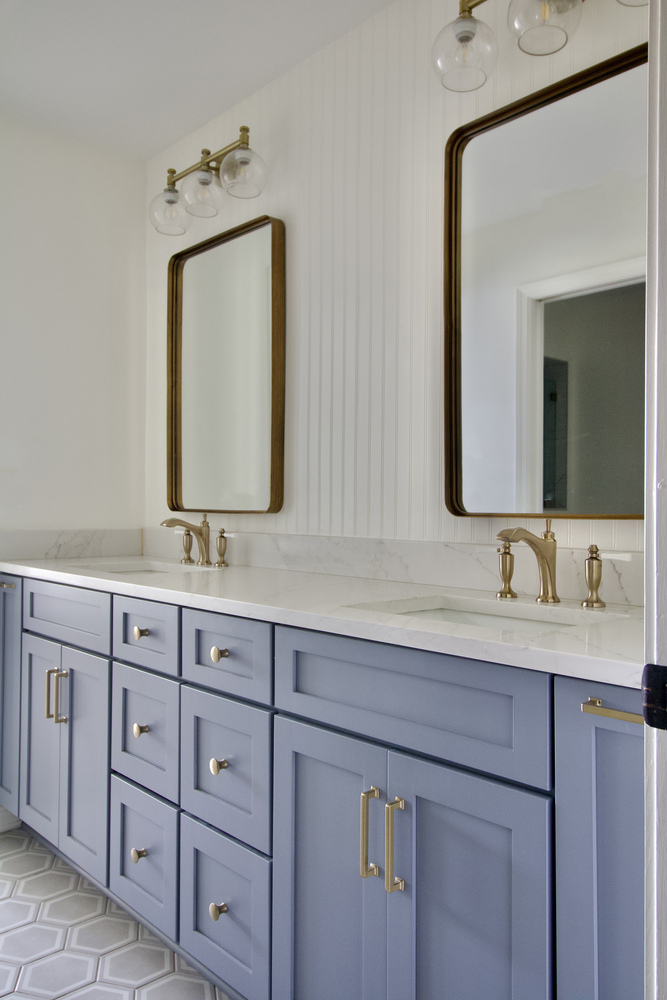 Double vanity with marble counters and blue cabinetry by Trade Works Remodeling in Louisville, KY