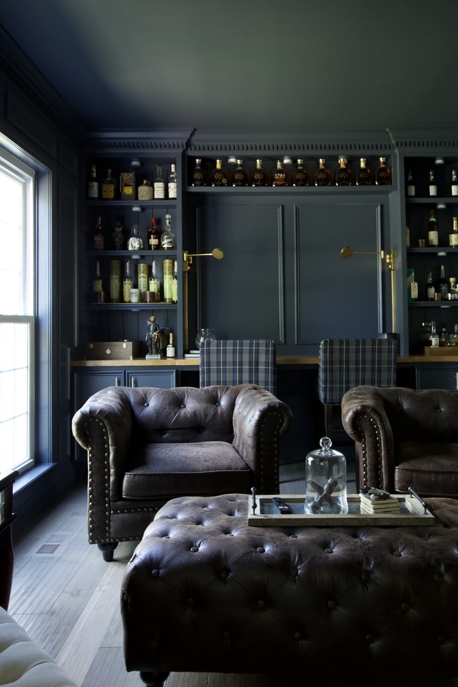 Inviting home bourbon lounge featuring a tufted leather set and bar seating by Trade Works Remodeling in Louisville