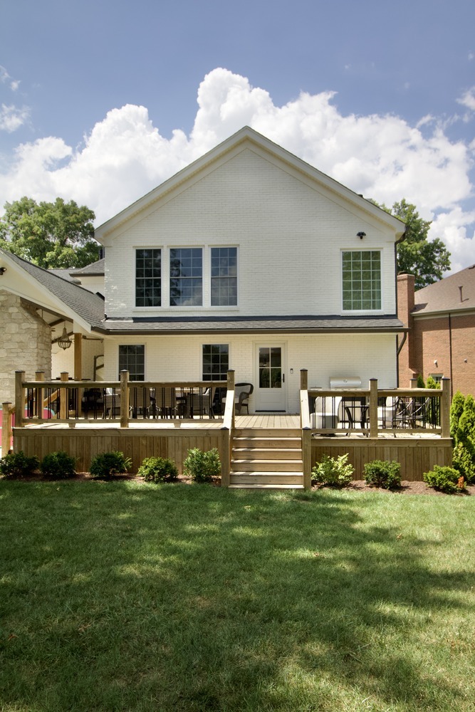 Rear exterior view of two-story white brick home with deck by Trade Works Remodeling in Louisville, KY