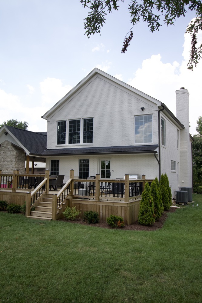 Side view of white painted brick home with raised deck by Trade Works Remodeling in Louisville, Kentucky