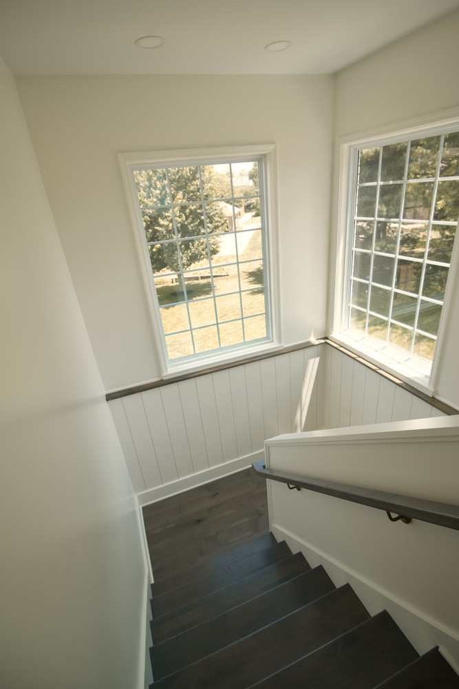 Upper stairwell with natural light and white trim in a Trade Works Remodeling custom home in Louisville, KY