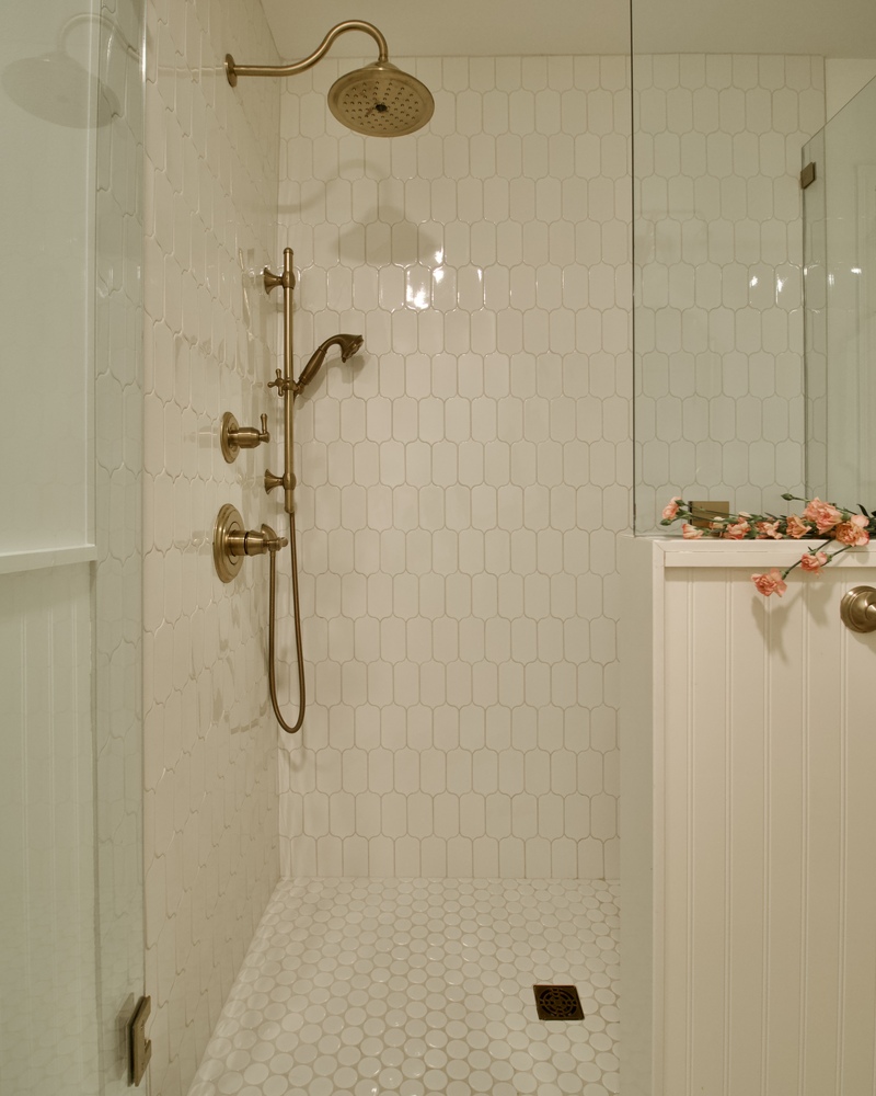 Walk-in shower with brass fixtures and white hexagon tiles in custom home by Trade Works Remodeling in Prospect, KY