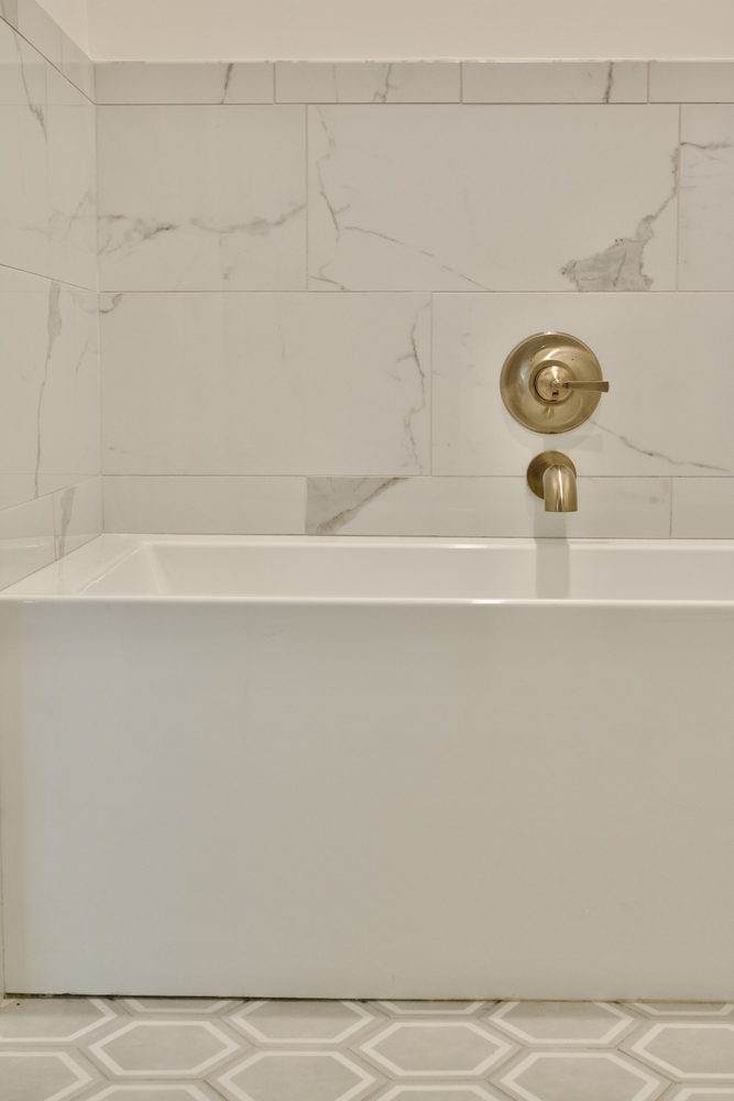 White bathtub with marble tile surround in custom bathroom by Trade Works Remodeling in Louisville, KY