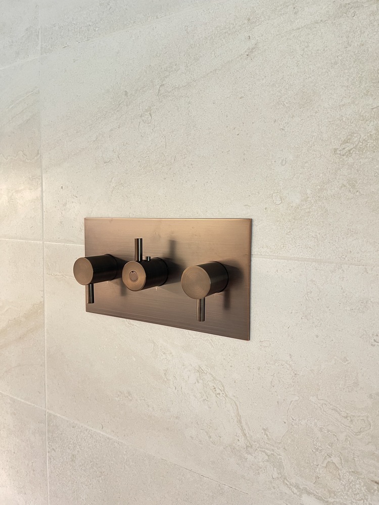 Close-up of custom bronze shower valve controls on tile wall in Ten Brook, KY by Trade Works Remodeling
