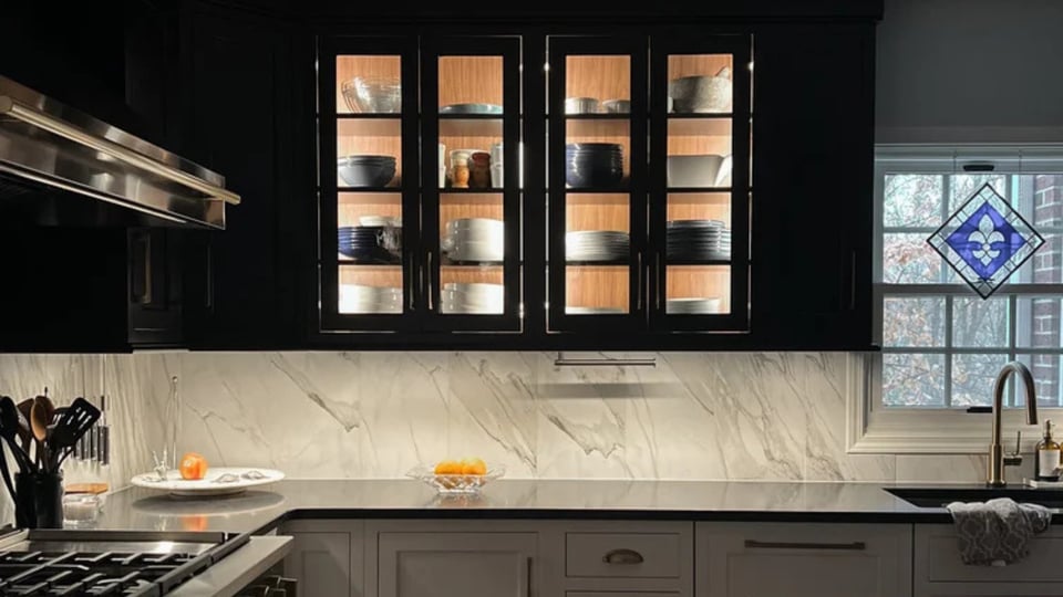 Illuminated upper cabinets with marble backsplash in luxury kitchen renovation