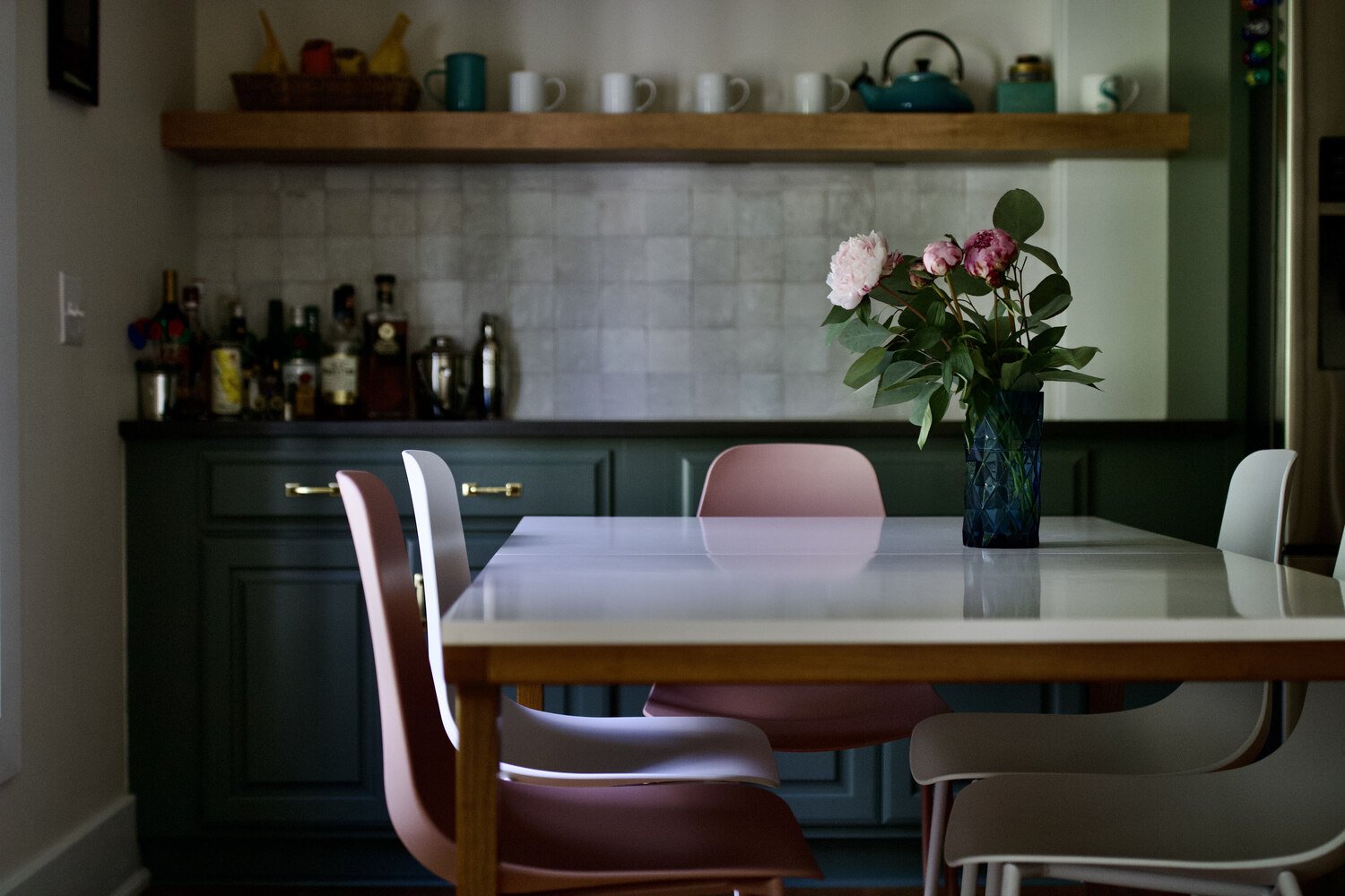 Modern dining area with green cabinetry and floral centerpiece in Louisville home by Trade Works Remodeling